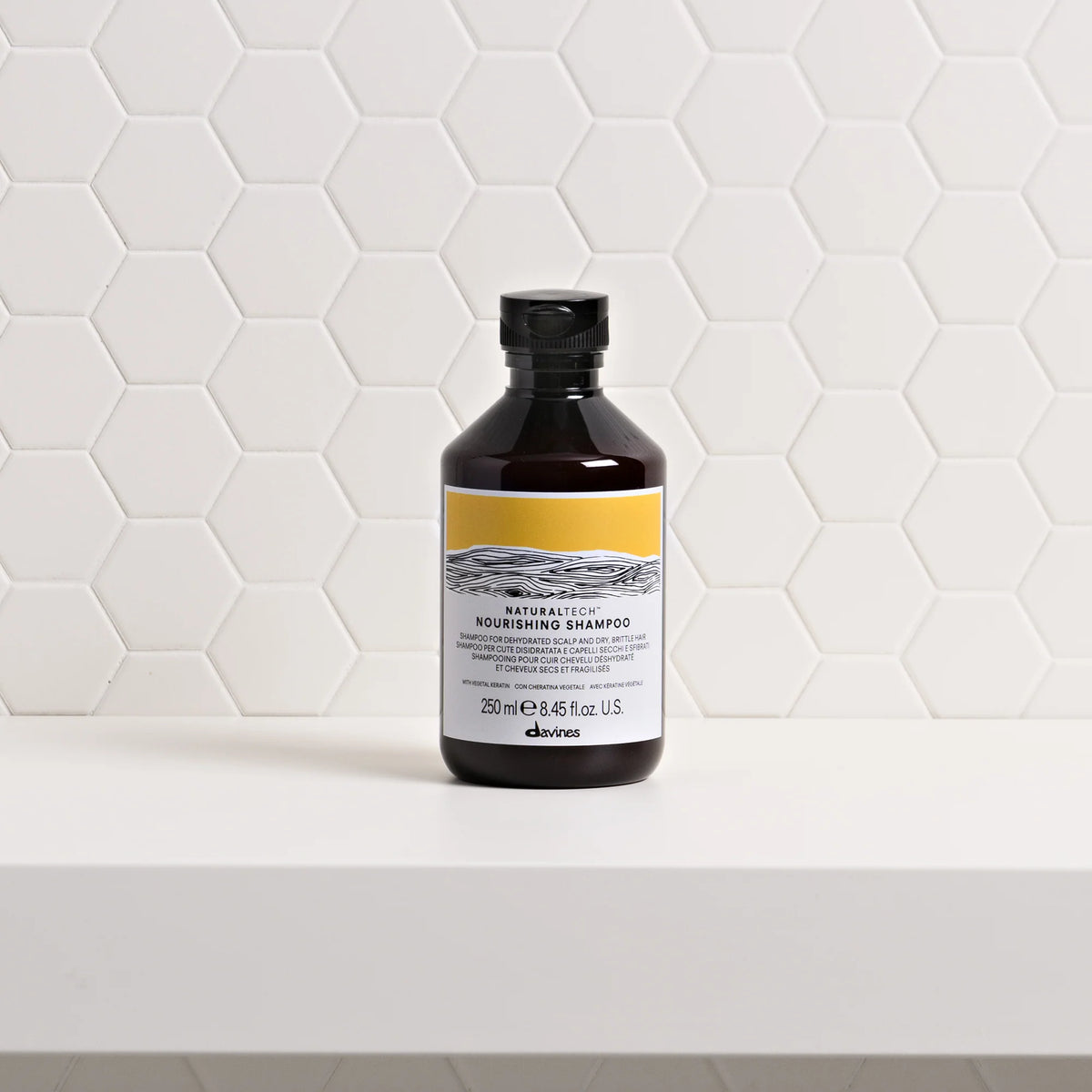 Davines Nourishing Shampoo 250 ml – flacon sur une étagère devant un carrelage blanc