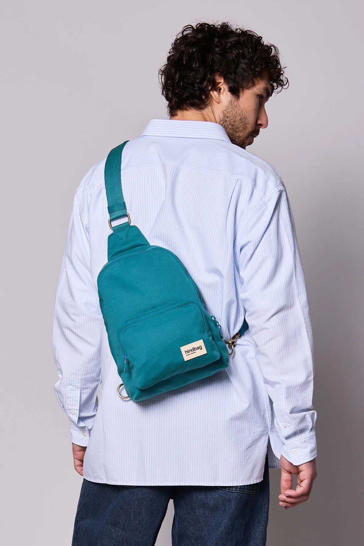Hindbag Sling Bag Felix coloris Bleu Paon porté dans le dos par un homme, sac bandoulière compact et pratique en coton épais