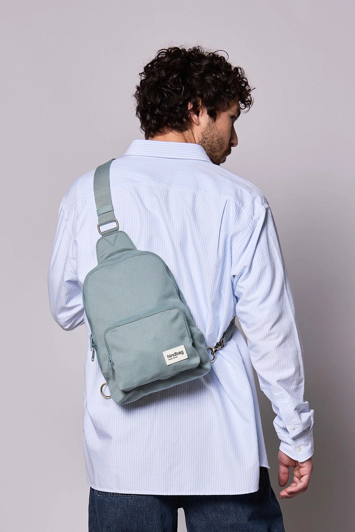 Hindbag Sling Bag Felix coloris Sauge porté dans le dos par un homme, sac compact unisexe pensé pour un usage urbain et quotidien