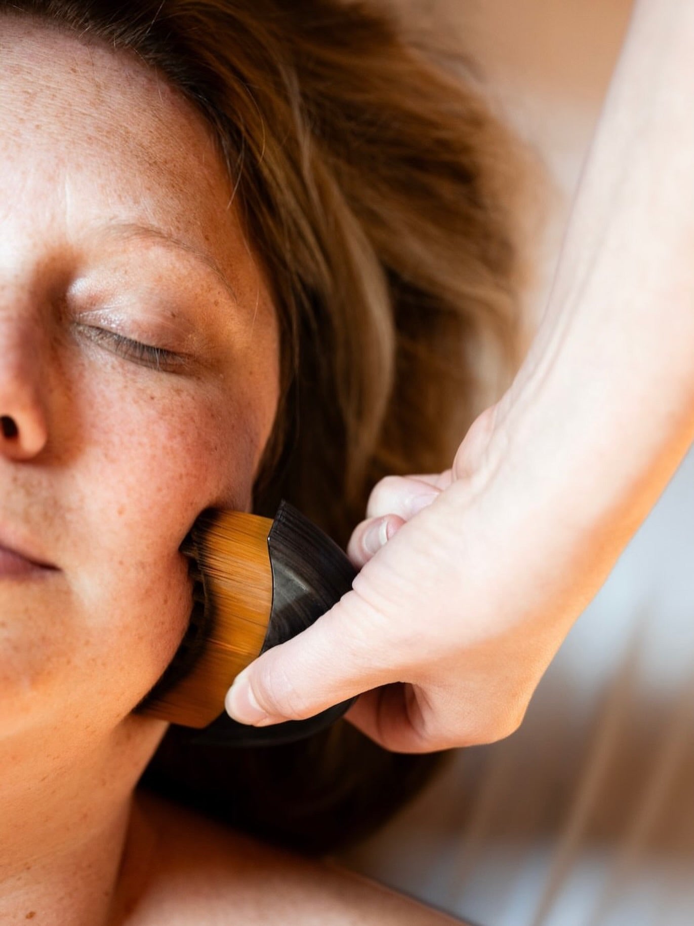 Utilisation de La Brosse Sculptante sur la joue, accessoire de massage visage pour accompagner les gestes de drainage, détendre les traits et raviver l’éclat de la peau