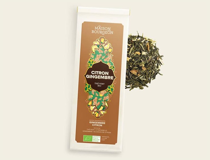 Thé vert bio Citron Gingembre de Maison Bourgeon avec un emballage élégant marron et or. À côté de l'emballage, un tas de feuilles de thé vert mélangé avec des morceaux de gingembre et des écorces de citron, mettant en avant les ingrédients naturels et aromatiques du thé.