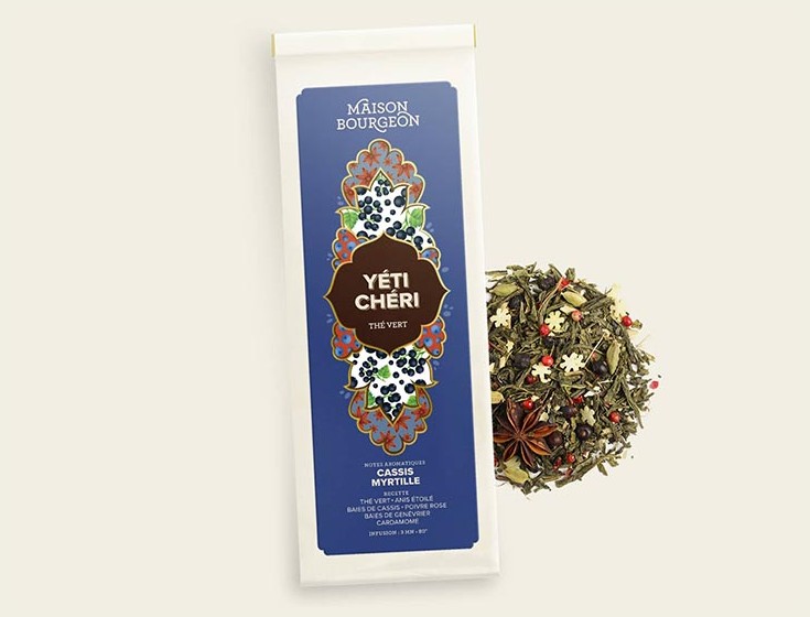 Photo du thé vert "Yéti Chéri" de la Maison Bourgeon. L'emballage bleu et élégant met en avant les notes aromatiques de cassis et de myrtille. À côté, on voit le mélange de feuilles de thé vert avec des épices et des fruits secs, notamment des baies de cassis, de la cardamome et de l'anis étoilé, qui enrichissent le thé de saveurs uniques et gourmandes. Ce thé est une création raffinée, parfaite pour les amateurs de saveurs fruitées et épicées.