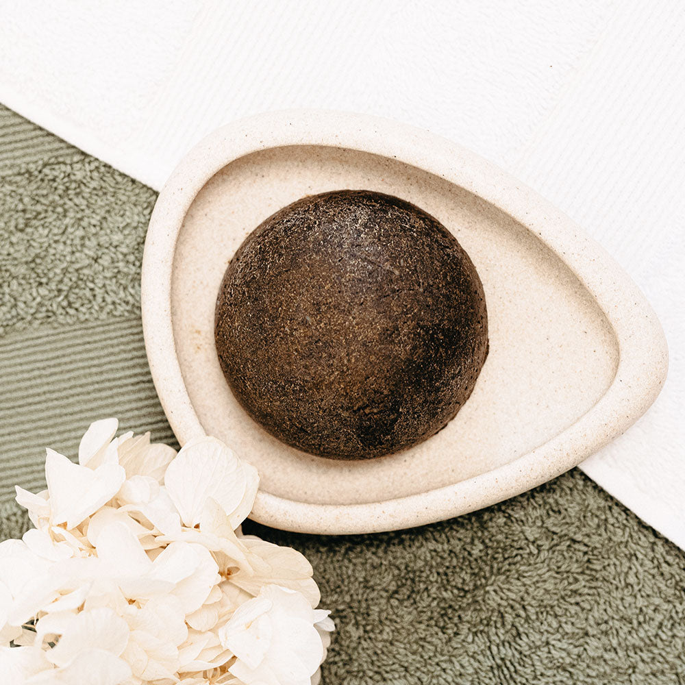 SHAMPOOING SOLIDE ÉQUILIBRANT Shampoing solide végétal équilibrant pour cheveux gras de Wilmotte Cosmétique, posé sur un porte-savon en céramique beige, avec fond naturel.