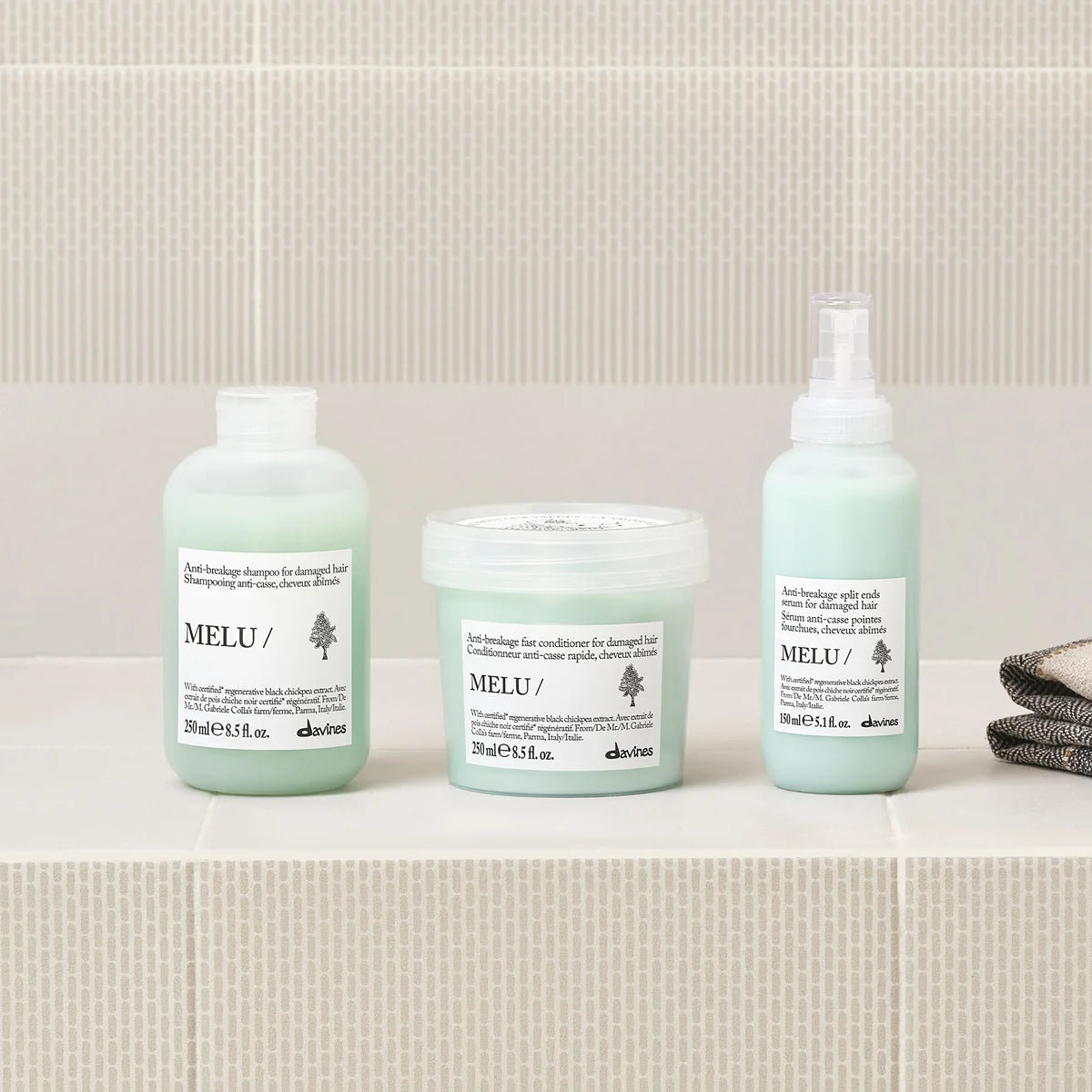 Shampooing, après-shampooing et sérum Davines MELU disposés sur une étagère de salle de bains