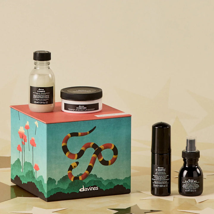 Coffret Davines OI Discovery avec produits OI sur fond beige et boîte illustrée d’un serpent stylisé.