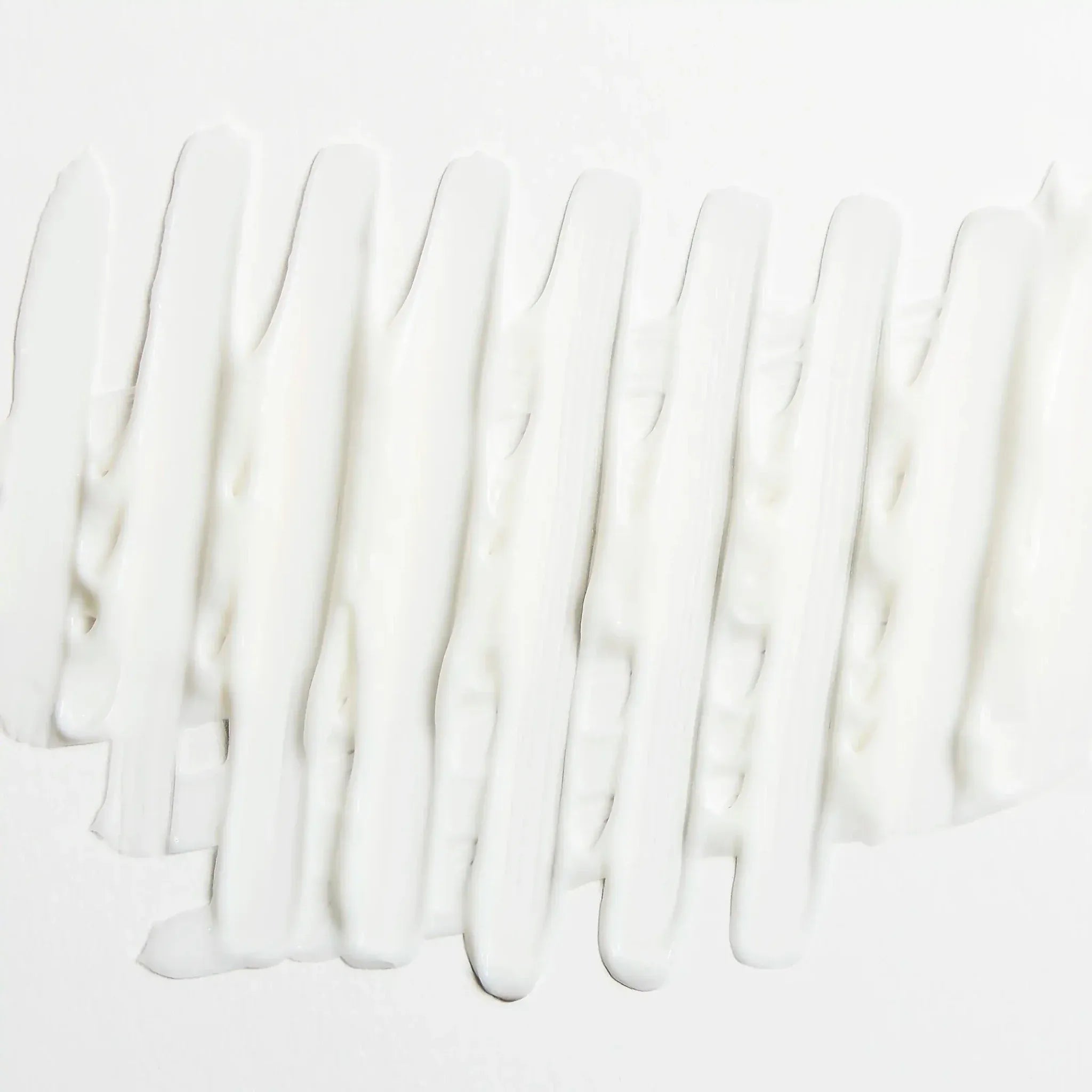 Texture blanche de la crème de jour anti-âge Endro Cosmétiques étalée sur fond clair.