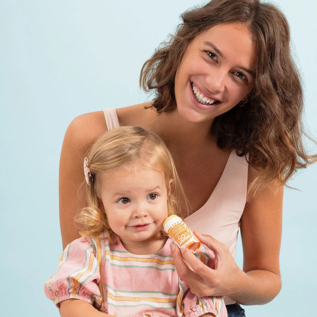 Maman appliquant le stick solaire Les Petits Prödiges SPF50 sur le visage de son enfant – protection solaire naturelle pour toute la famille