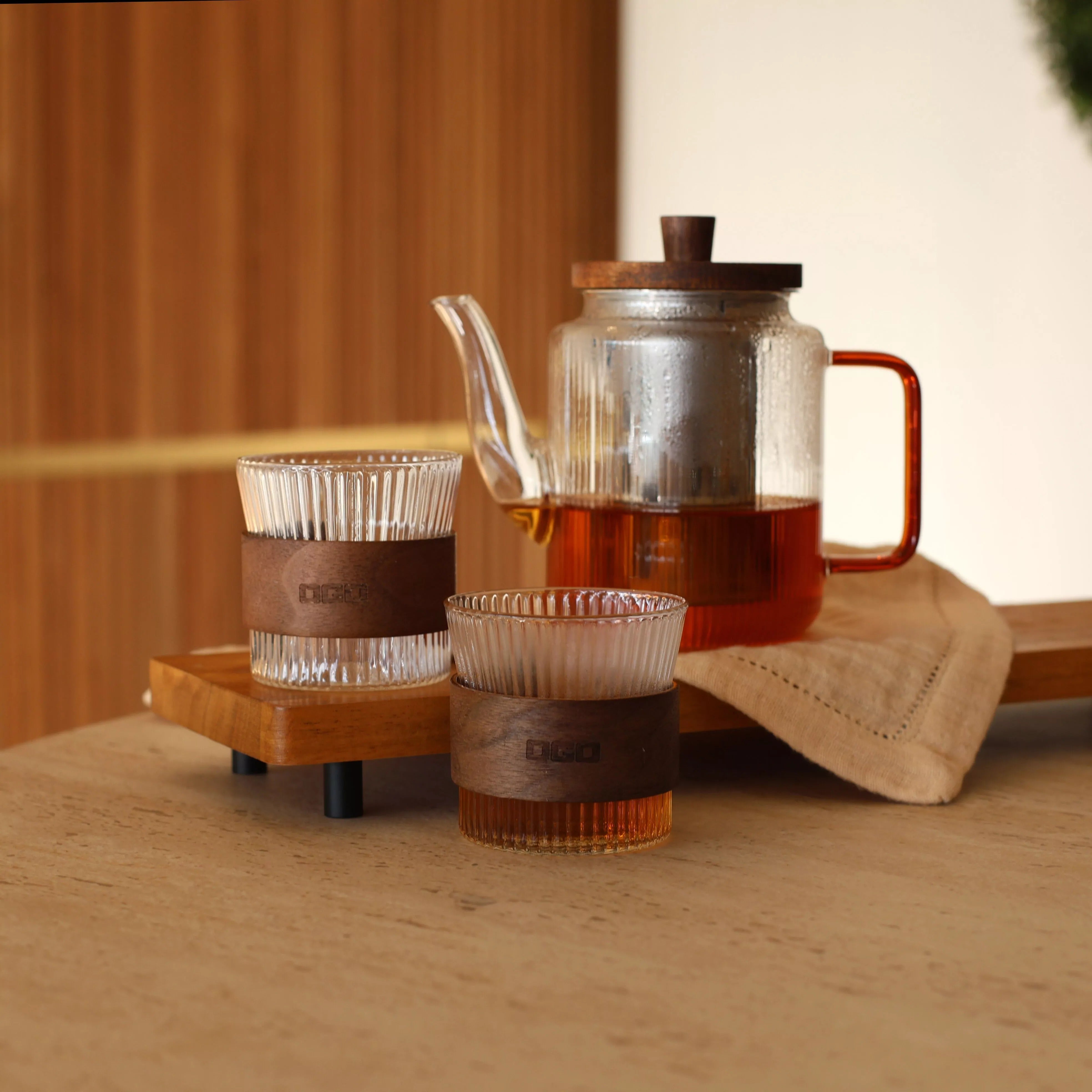 Théière OGO Living KARL remplie de thé chaud avec deux tasses nervurées au bandeau bois assorti