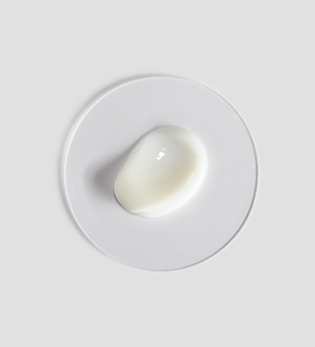 Gros plan sur la texture du "Body Strategist Cryo Leg Gel" de Comfort Zone. Le gel est blanc, affiché sur une surface circulaire transparente, posée sur un fond gris clair.