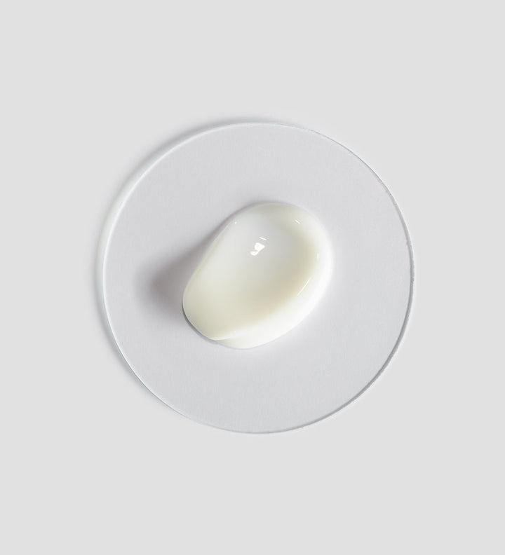 Gros plan sur la texture du "Body Strategist Cryo Leg Gel" de Comfort Zone. Le gel est blanc, affiché sur une surface circulaire transparente, posée sur un fond gris clair.