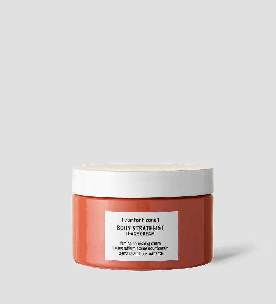 Pot de "Body Strategist D-Age Cream" de Comfort Zone, affiché sur un fond gris clair. La crème est étiquetée comme "firming nourishing cream" en anglais, français et italien, indiquant ses propriétés raffermissantes et nourrissantes.