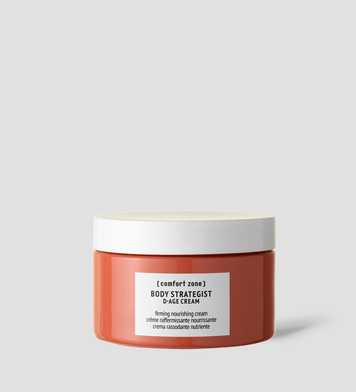 Pot de "Body Strategist D-Age Cream" de Comfort Zone, affiché sur un fond gris clair. La crème est étiquetée comme "firming nourishing cream" en anglais, français et italien, indiquant ses propriétés raffermissantes et nourrissantes.
