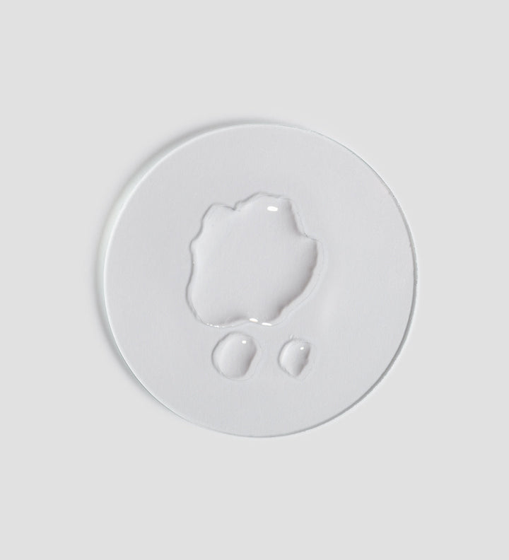Gros plan de la texture du toner apaisant Remedy de Comfort Zone, montré sur un fond blanc clair. Le toner est translucide et présente une texture liquide.