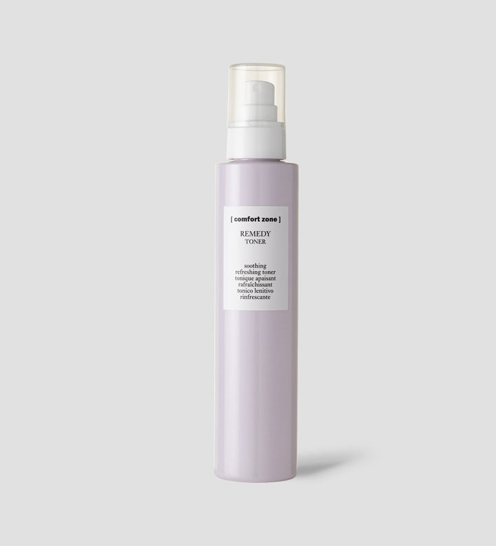 Flacon de toner apaisant Remedy de Comfort Zone sur un fond gris clair. Le flacon est violet clair avec un bouchon transparent et une étiquette blanche indiquant "Remedy Toner".