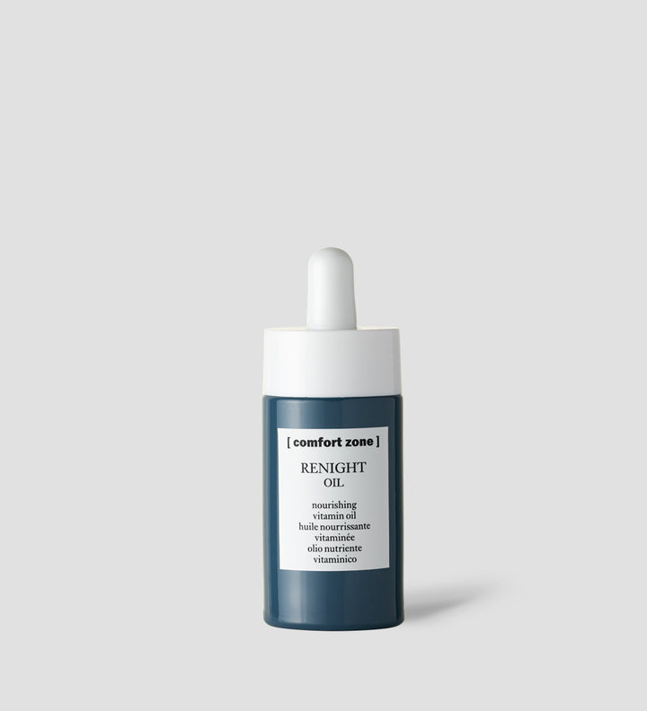 Flacon d'huile Renight de Comfort Zone sur fond gris clair. Étiquette indiquant "Renight Oil, nourishing vitamin oil" en noir et blanc.