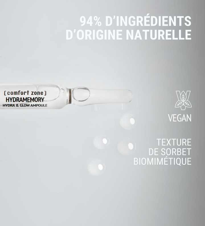 Affiche publicitaire de [comfort zone] pour les ampoules Hydramemory Hydra & Glow. L'image met en avant une ampoule avec la mention "94% d'ingrédients d'origine naturelle" et des gouttes à côté. Le produit est marqué comme étant vegan avec une texture de sorbet biomimétique, sur un fond gris clair.