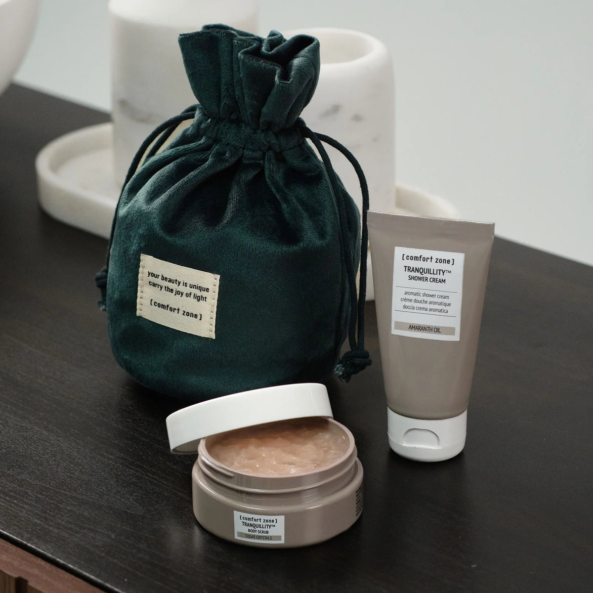 Gommage Tranquillity et crème de douche du coffret The Body Ritual On The Go présentés avec le pochon vert.