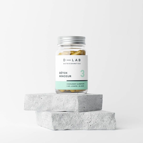Bouteille de compléments alimentaires D-LAB Nutricosmetics Détox Minceur posée sur des blocs de béton.