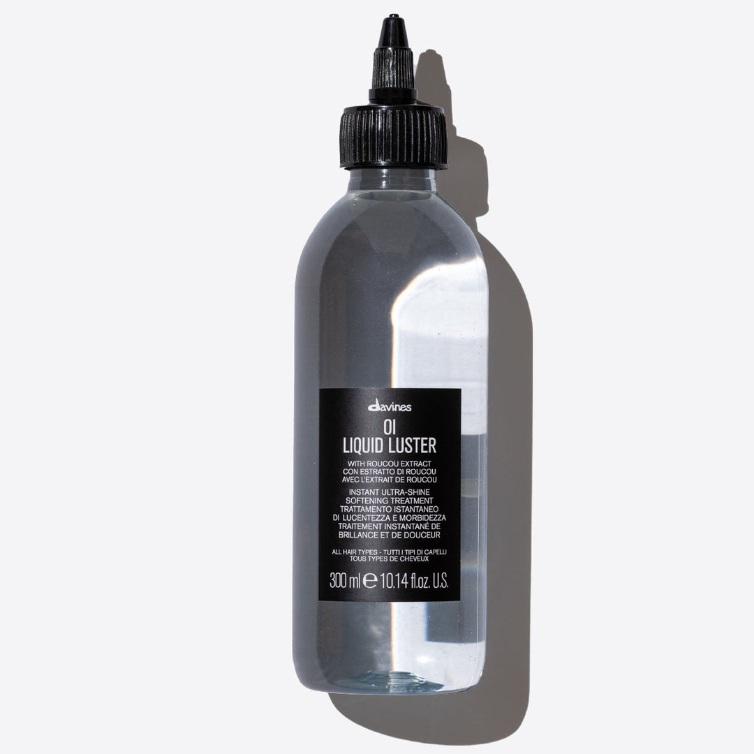 Bouteille de Davines OI Liquid Luster avec extrait de Roucou. Un traitement adoucissant et instantané qui apporte brillance et douceur à tous types de cheveux. La bouteille transparente de 300 ml contient un liquide clair et est munie d'un bouchon noir à vis.