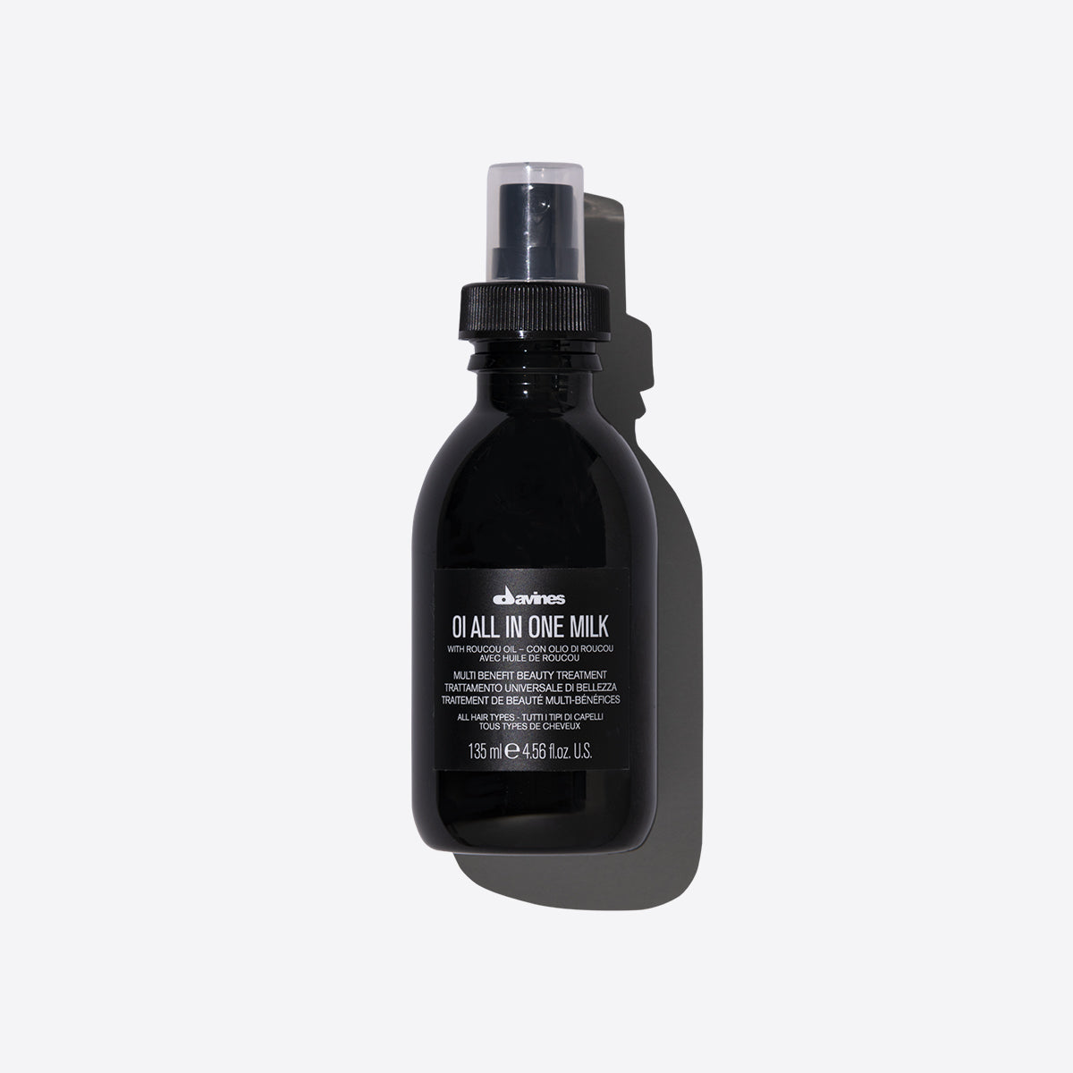 Une bouteille noire élégante de 135 ml du lait multifonction "OI All In One Milk" de Davines. Le produit, présenté en format spray, est formulé avec de l'huile de Roucou, connue pour ses propriétés nourrissantes et protectrices. Ce traitement beauté multifonctionnel est conçu pour hydrater, démêler, contrôler les frisottis et ajouter de la brillance aux cheveux. Parfait pour un usage quotidien, il convient à tous les types de cheveux et offre un soin complet en un seul geste.