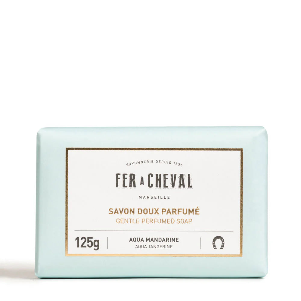 Image du savon doux parfumé de la marque Fer à Cheval. L'emballage est de couleur bleu pâle avec une étiquette blanche et dorée indiquant le nom de la marque et du produit. Ce savon est parfumé à l'aqua mandarine et pèse 125g. On voit clairement le logo du fer à cheval ainsi que les mentions en anglais "Gentle Perfumed Soap" et "Aqua Mandarine"