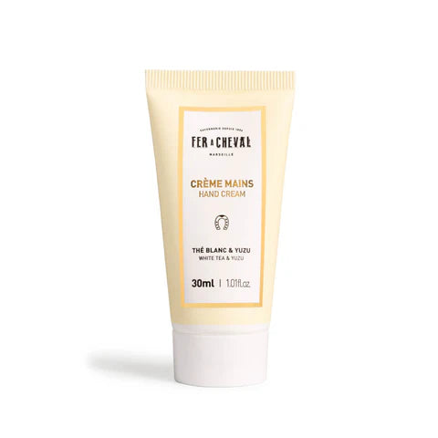 Image d'un tube de crème pour les mains de la marque Fer à Cheval. Le tube est de couleur beige avec un bouchon blanc et porte l'inscription "Crème Mains Thé Blanc & Yuzu" en lettres dorées. Il contient 30 ml de produit.