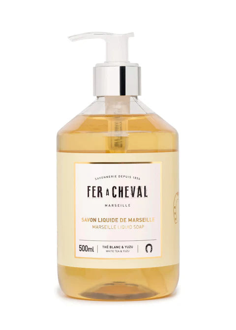 Image d'un flacon de savon liquide de Marseille de la marque Fer à Cheval. Le flacon transparent avec une pompe contient un savon liquide de couleur ambrée. L'étiquette indique "Savon Liquide de Marseille" parfumé au thé blanc et yuzu, avec une capacité de 500ml.
