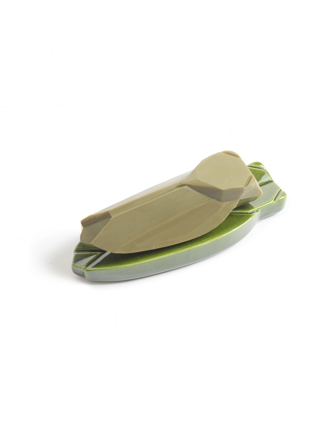 Image montrant un savon en forme de cigale posé sur son porte-savon assorti, issus de l'association entre Fer à Cheval et Monochromic. Le savon est de couleur beige et le porte-savon est vert, tous deux avec une forme géométrique stylisée rappelant une cigale.
