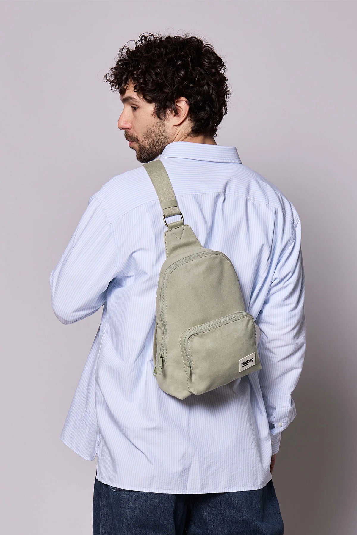Hindbag Sling Bag Felix coloris Argile porté dans le dos par un homme, sac compact et ergonomique pour accompagner les déplacements du quotidien