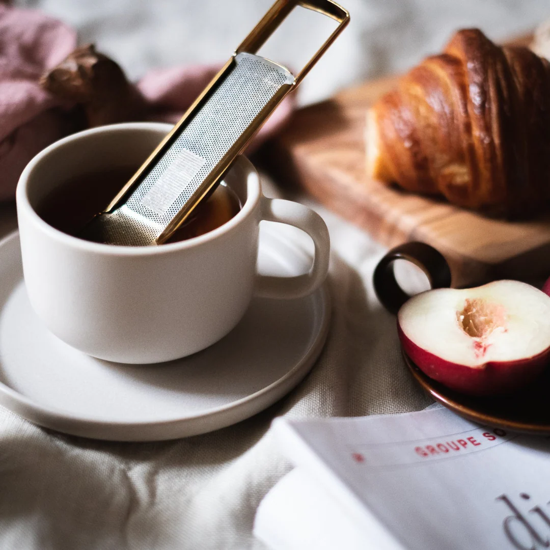 Infuseur à thé Drosselmeyer Tesil utilisé dans une tasse de thé avec croissant et fruit