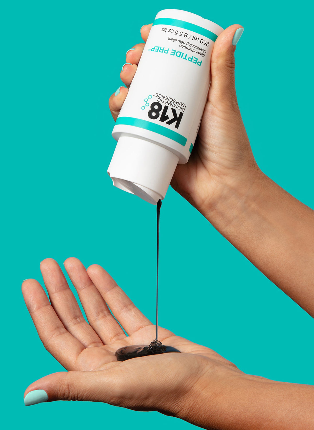 Une main verse le shampooing clarifiant K18 Peptide Prep Detox 250 ml dans une paume, sur fond turquoise.