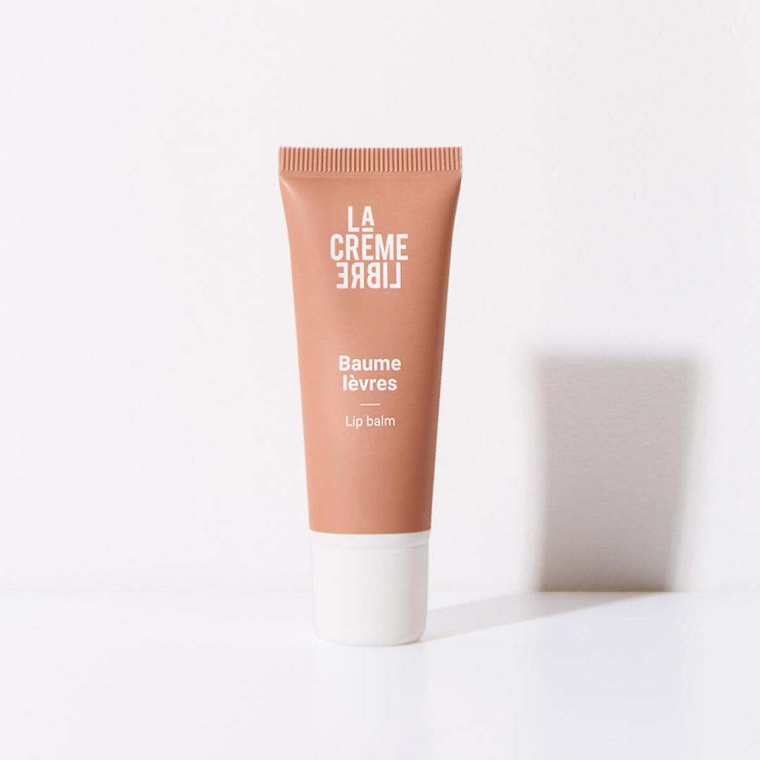 BAUME LÈVRES NOURRISSANT & RÉPARATEUR Packshot du Baume Lèvres La Crème Libre, présenté dans un tube rose poudré sur fond blanc. Design épuré mettant en valeur la texture nourrissante du soin hydratant.