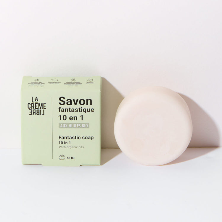 Savon solide 10 en 1 La Crème Libre en packshot, cosmétique bio minimaliste pour le visage, le corps et les usages multiples. Formulé aux huiles bio pour un nettoyage doux, sans assécher la peau. Visuel montrant le savon rond et sa boîte verte sur fond clair.
