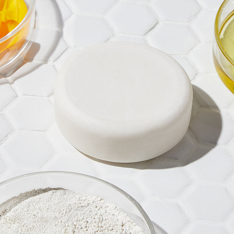 Savon Fantastique 10 en 1 de LA CRÈME LIBRE, soin solide naturel multi-usages sans savon, présenté sur un carrelage blanc avec des ingrédients bruts visibles, dans un style épuré et lumineux

