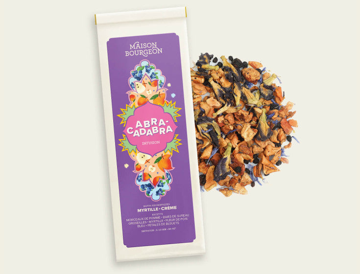 Image du produit Abracadabra de la marque Maison Bourgeon. L'emballage est violet avec des motifs floraux, et le contenu de l'infusion, composé de morceaux de pomme, baies de sureau, groseilles, myrtilles, fleur de pois bleu et pétales de bleuets, est visible à côté.