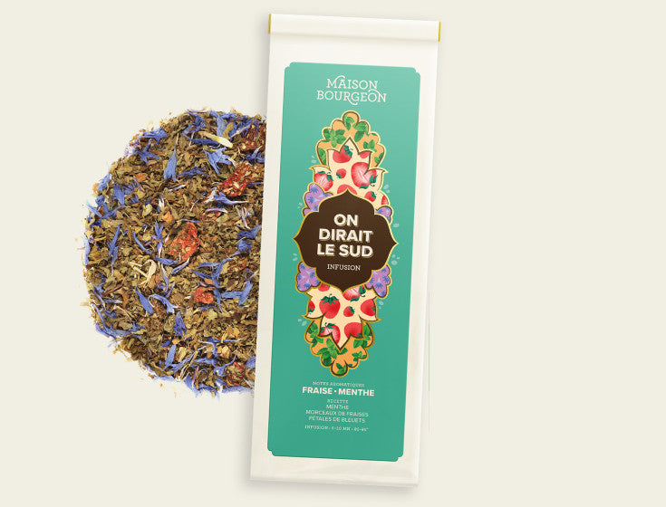 Maison Bourgeon On Dirait Le Sud Infusion, un sachet d'infusion avec un mélange de fraise et de menthe visible à côté du paquet. L'emballage est vert avec des illustrations de fraises et de menthe. Noté pour ses arômes naturels.