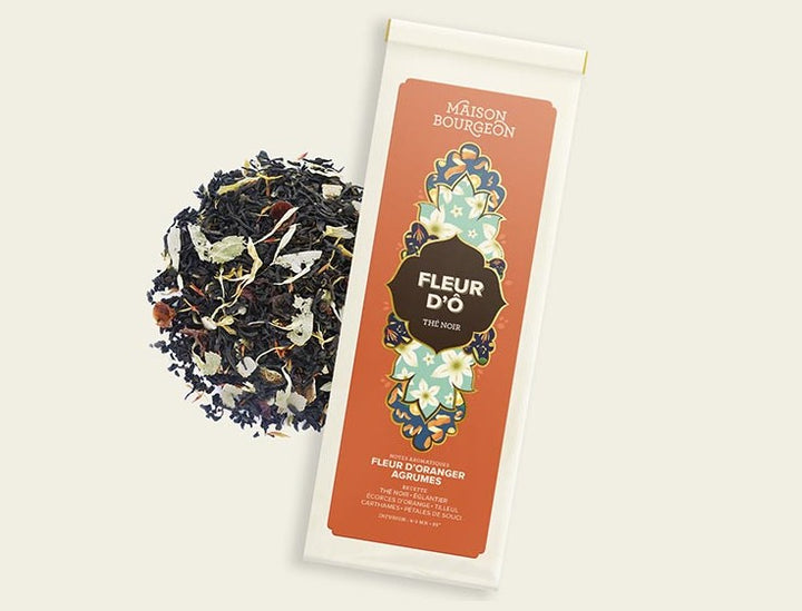 Image du produit "FLEUR D'Ö" de la marque Maison Bourgeon, montrant un paquet de thé noir aromatisé avec des saveurs de fleur d'oranger et d'agrumes. Le paquet est à côté d'un mélange de thé en vrac, mettant en valeur les morceaux d'écorces d'orange, les pétales de fleurs et autres ingrédients naturels visibles dans le thé.