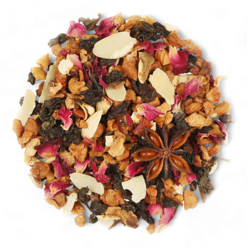 Mélange de thé Oolong La Féérie des Lutins de Maison Bourgeon en gros plan. Infusion gourmande aux morceaux de pomme, amandes effilées, écorces d'orange, anis étoilé, pétales de rose et épices. Un thé de Noël chaleureux aux saveurs fruitées d'abricot et de mandarine, idéal pour l'hiver et les fêtes de fin d'année.
