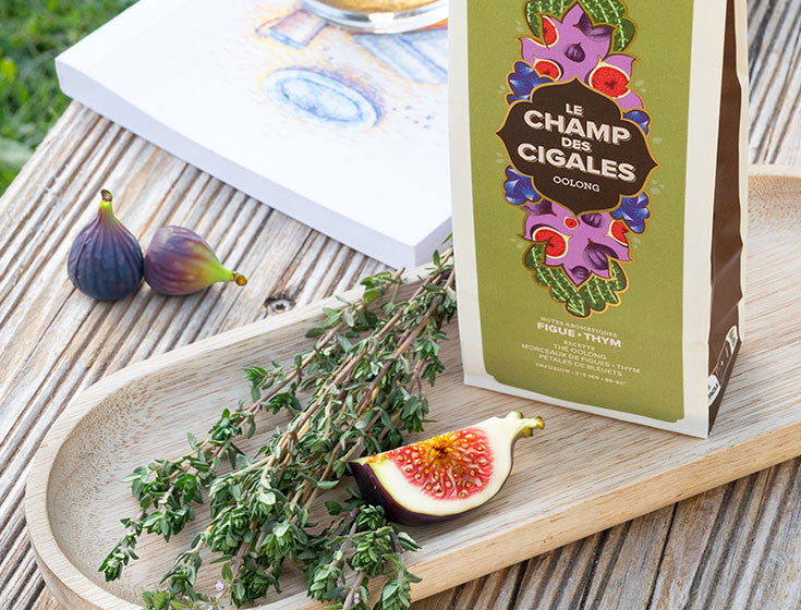 Oolong Le Champ des Cigales de Maison Bourgeon, accompagné de figues fraîches et de branches de thym, illustrant les saveurs méditerranéennes et aromatiques de cette infusion raffinée parfaite pour un moment de détente en plein air.