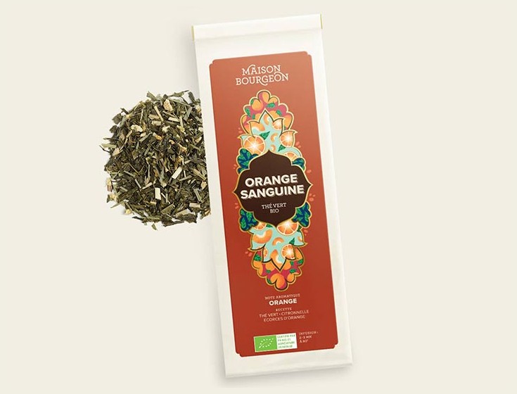 Paquet de thé vert bio Maison Bourgeon Orange Sanguine avec un mélange de thé vert et de morceaux d'orange à côté du paquet.