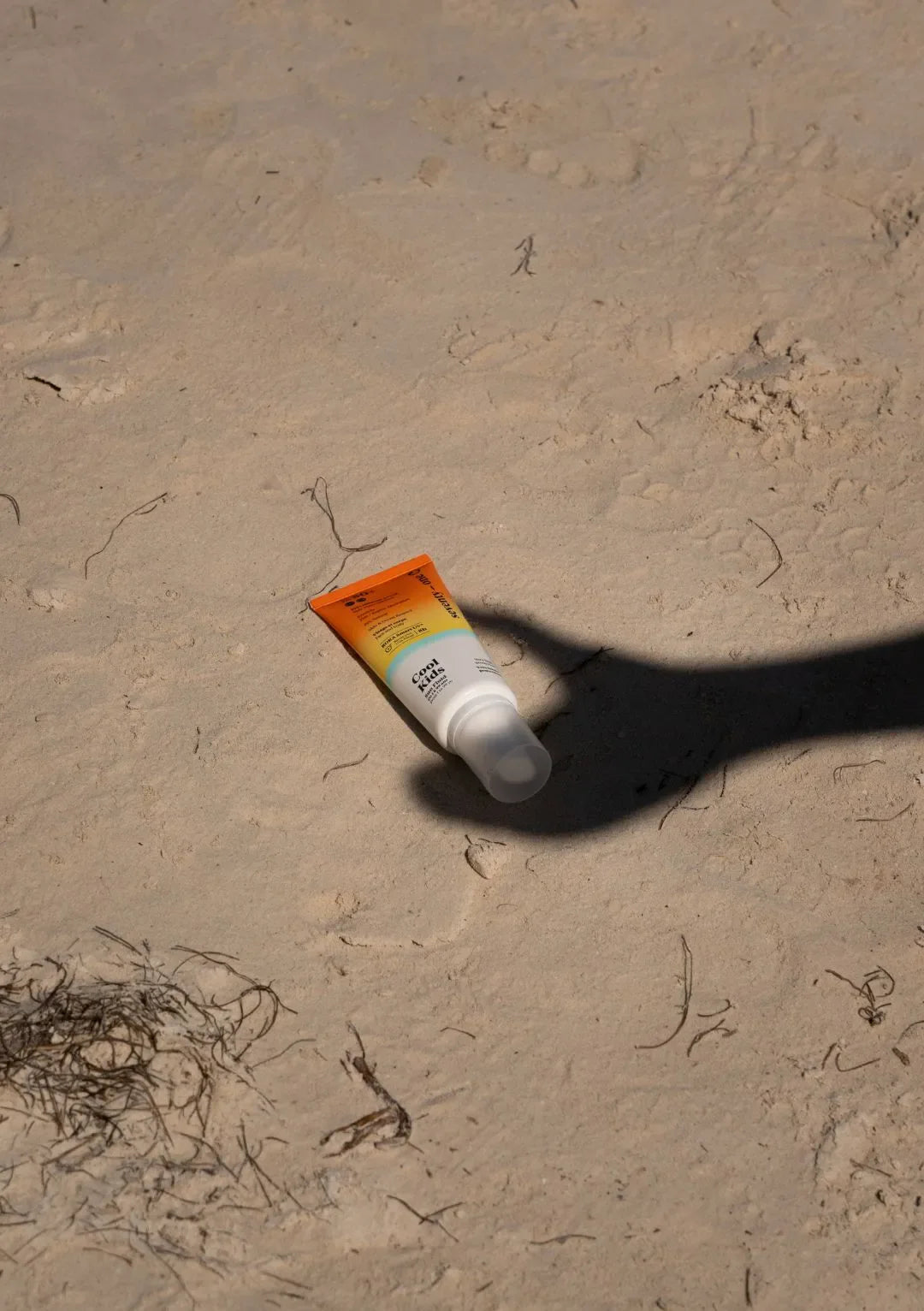 SeventyOne Percent Sun Kissed Lotion SPF50+ posée sur le sable, protection solaire invisible visage et corps pour accompagner les journées à la plage